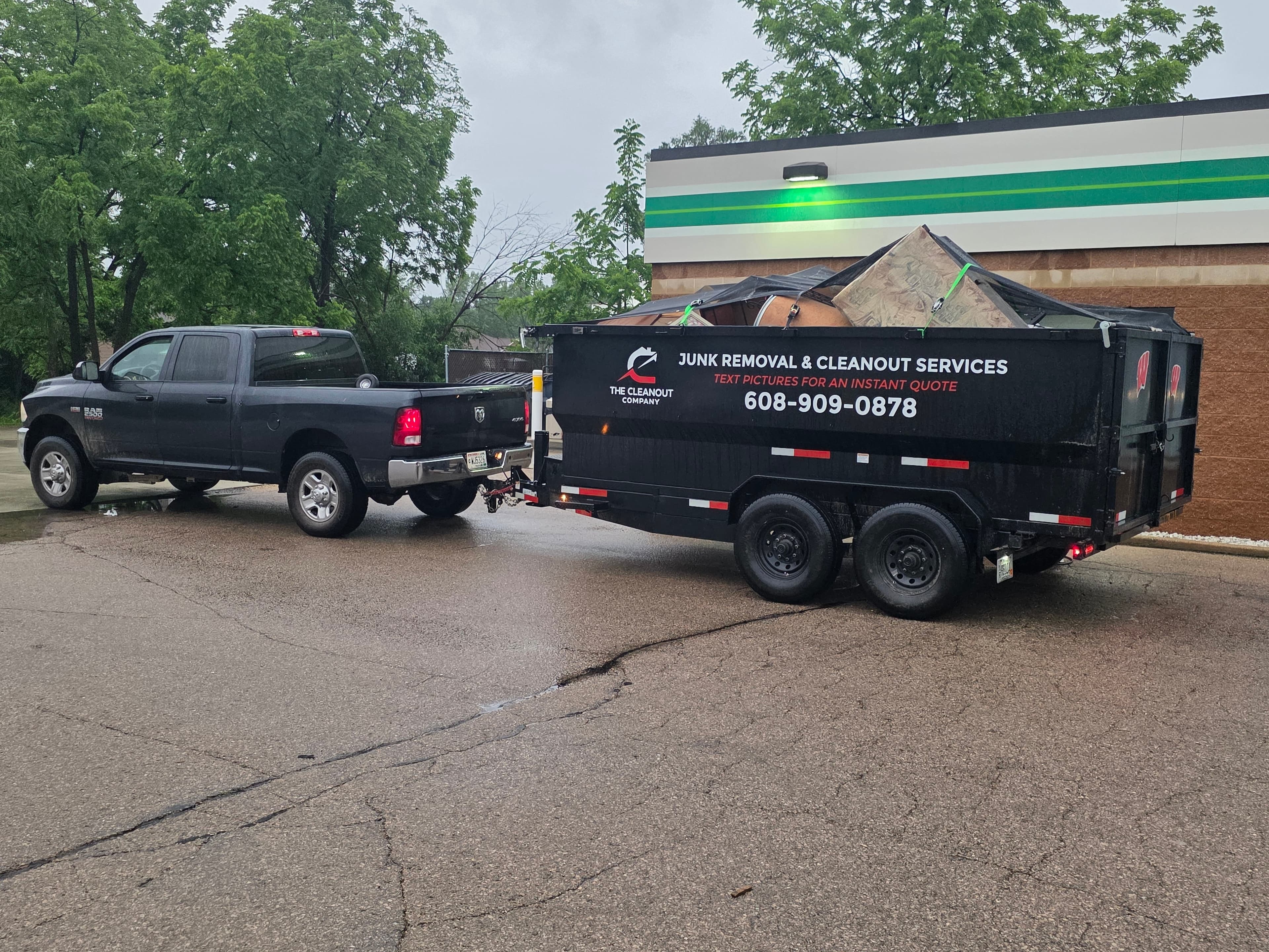 Cleanout Company trailer overfilled above the sides with furniture and debris, tarped and strapped down