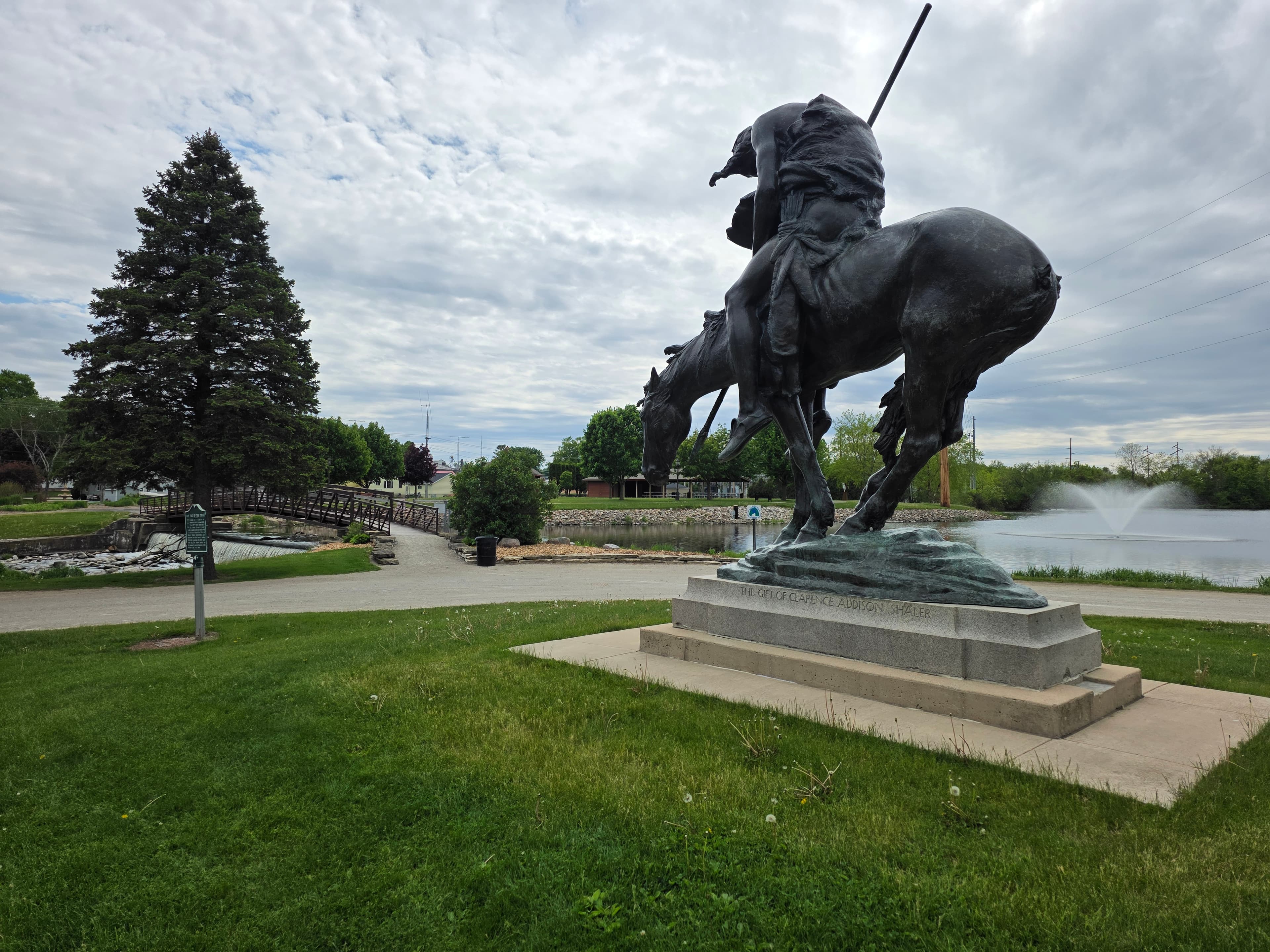 Flat Iron Park in Waupun, WI featuring the iconic equestrian statue, pond, and footbridge